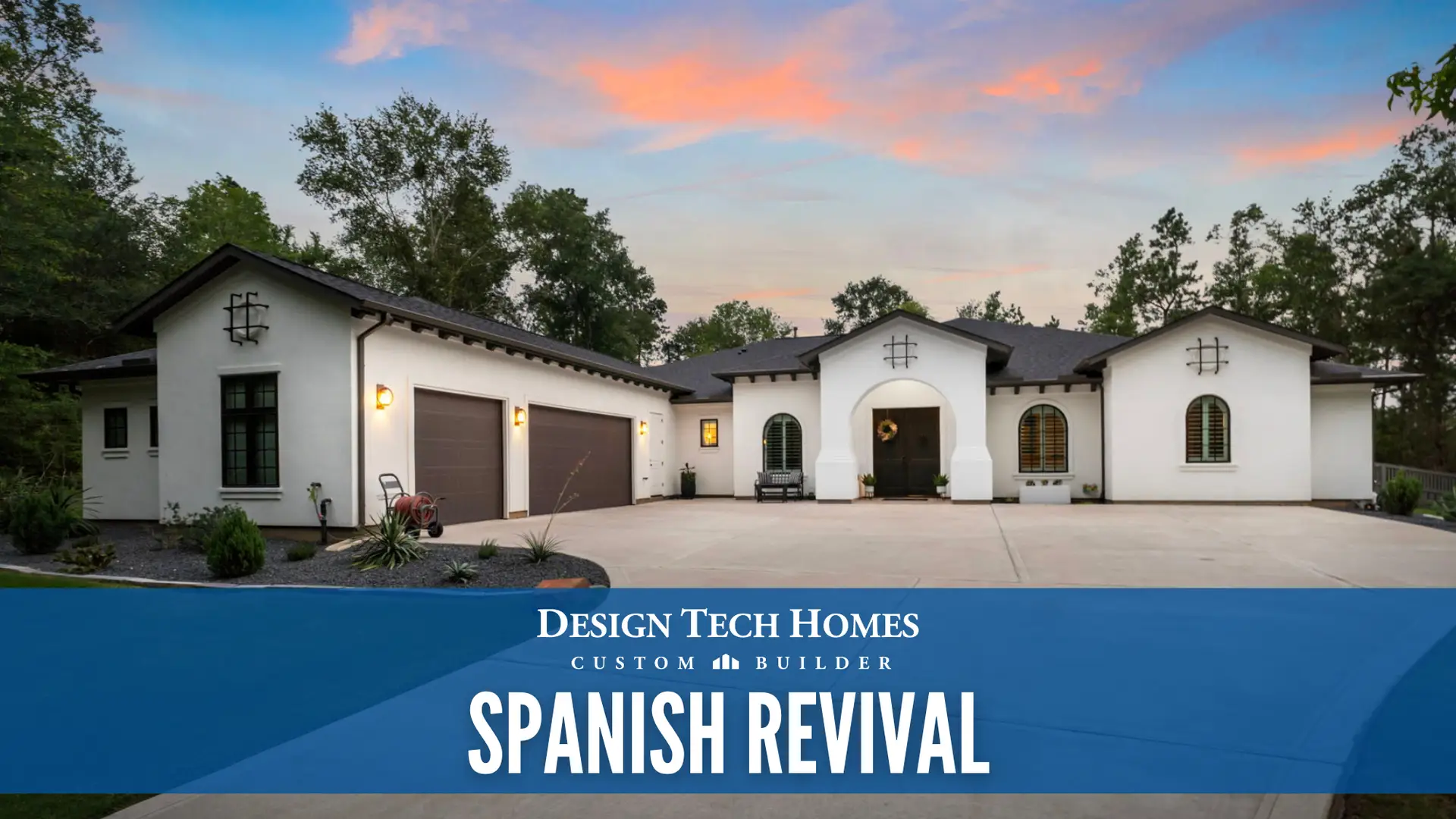 Spanish Revival custom home with white stucco exterior, arched entryway, tile roof, wooden shutters, and wide driveway at sunset with trees