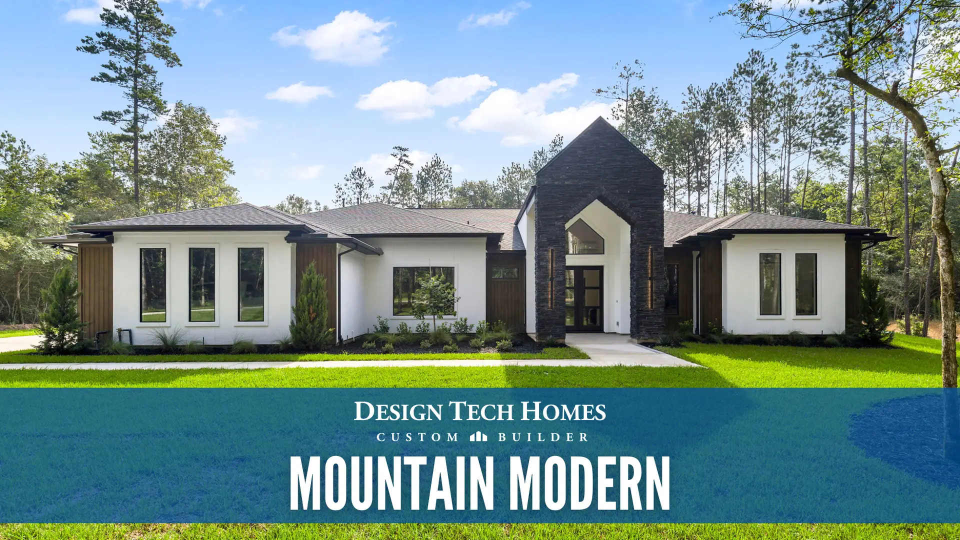 Mountain Modern custom home with white stucco exterior, tall dark stone entry tower, gabled roof, large windows, and wood accents surrounded by pine trees under blue sky