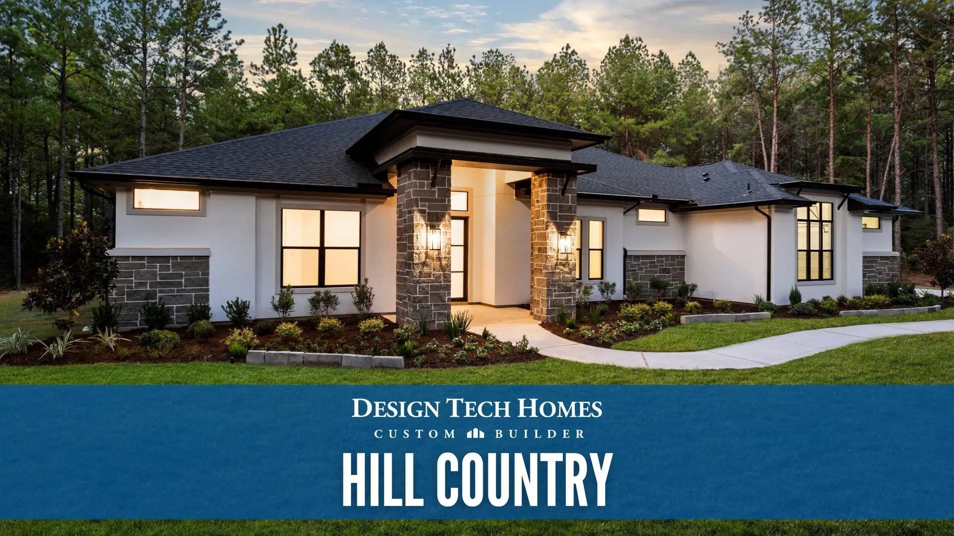 Custom home exterior with white stucco, stone columns, black trim, and illuminated entry at dusk surrounded by pine trees