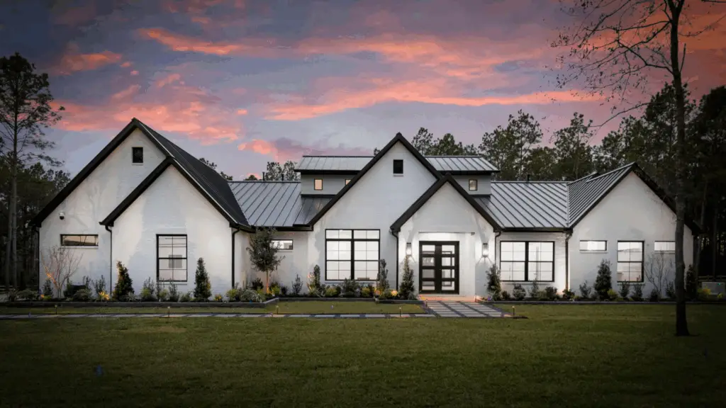 Modern custom home exterior with white brick façade and metal roof at sunset