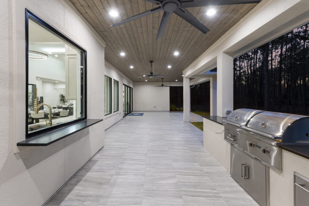 Covered outdoor kitchen with full-length counters and built-in grill at Design Tech Homes model in The Estates of Texas Grand Ranch.