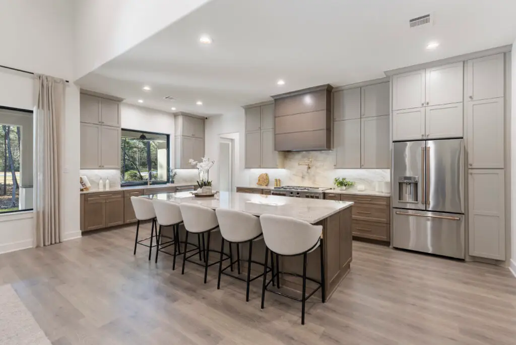 Kitchen with large island in Design Tech Homes showcase model at the Estates of Texas Grand Ranch featuring custom cabinetry and open layout