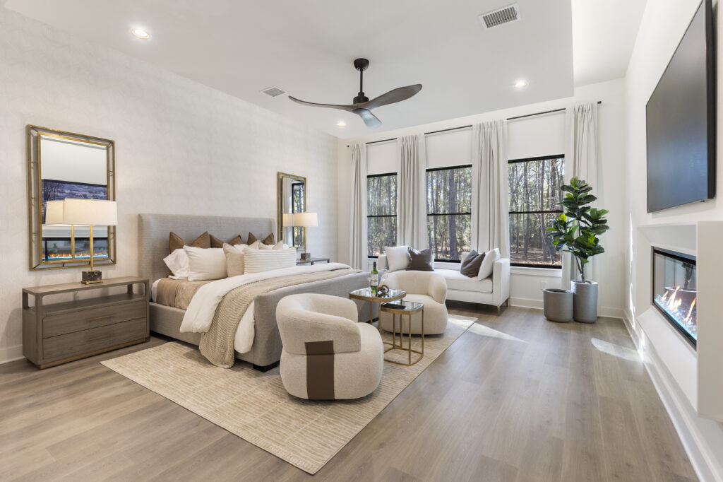 Bright, modern bedroom with a neutral color palette, upholstered bed, seating area, and large windows with French doors leading outside.